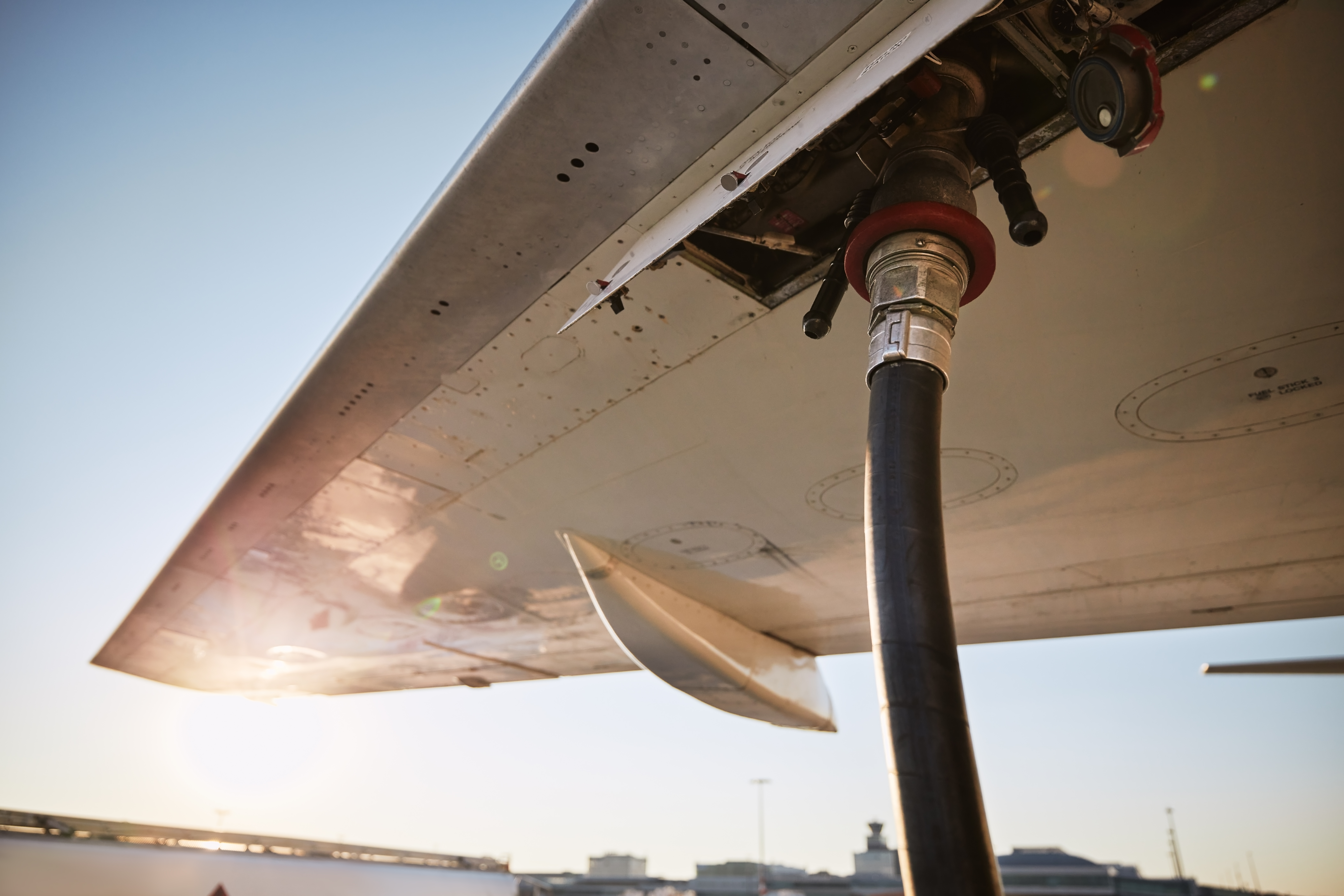 Aircraft wing being refuelled on stand at sunset